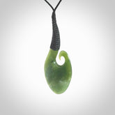 This picture shows a large deep green large jade koru pendant, also called a koru, carved for us in New Zealand jade. The cord is a four-plait, adjustable black coloured necklace.